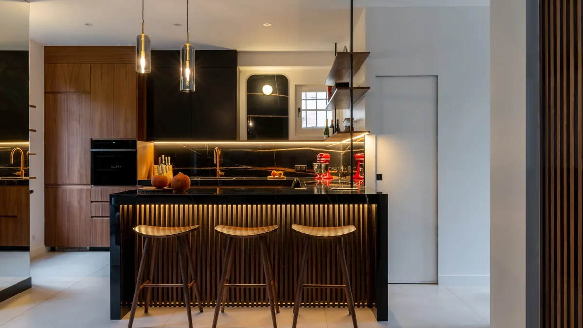 Cuisine ouverte en noyer et marbre noir avec comptoir à tasseaux éclairé, maison rénovée à L'Haÿ-les-Roses, projet Larroumes par Ameo Concept